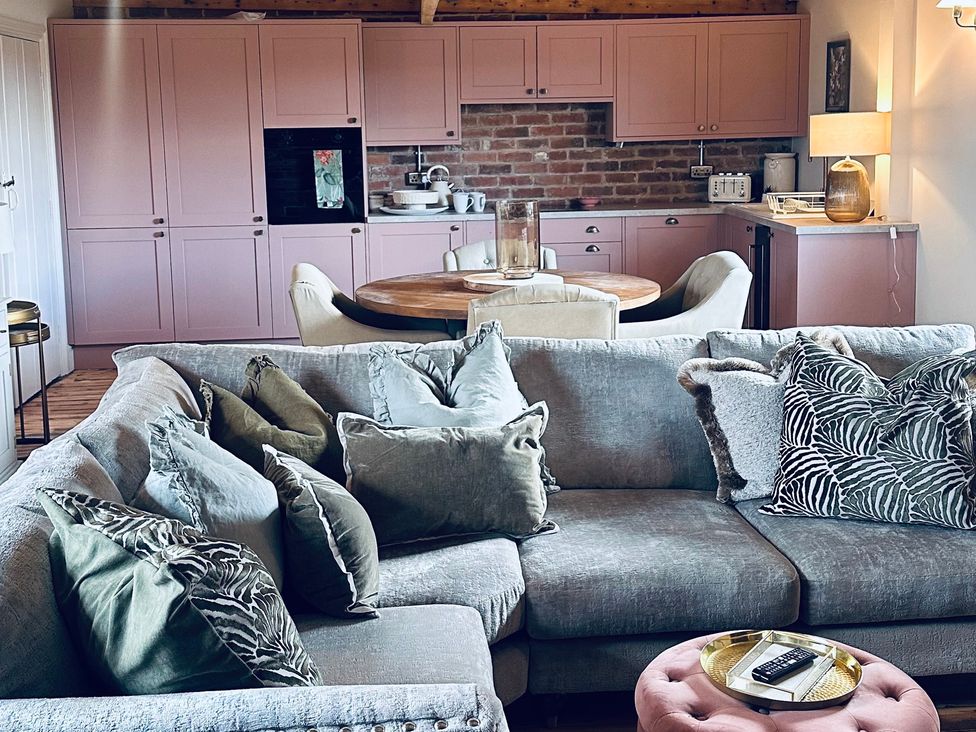 A living room with a sofa and kitchen in Farnah House Barn in Duffield