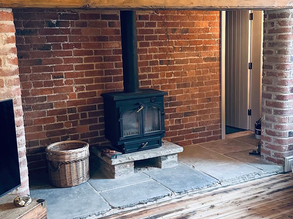 A living room with a stove near a brick wall at Farnah House Barn in Duffield