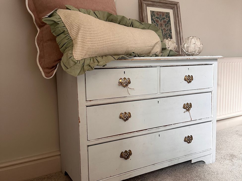 A chest of drawers with pillows and a picture frame at Farnah House Barn in Duffield