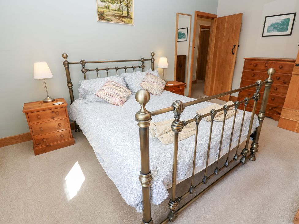 A bedroom with a bed, nightstand, and chest of drawers at Bridge House