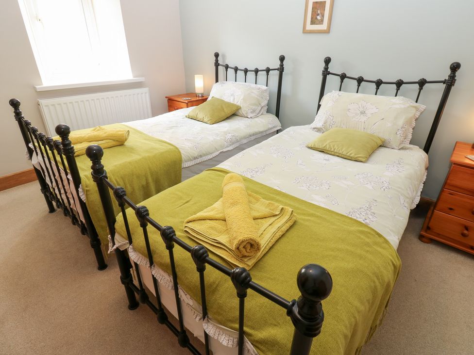 A bedroom with twin beds and a nightstand at Bridge House 