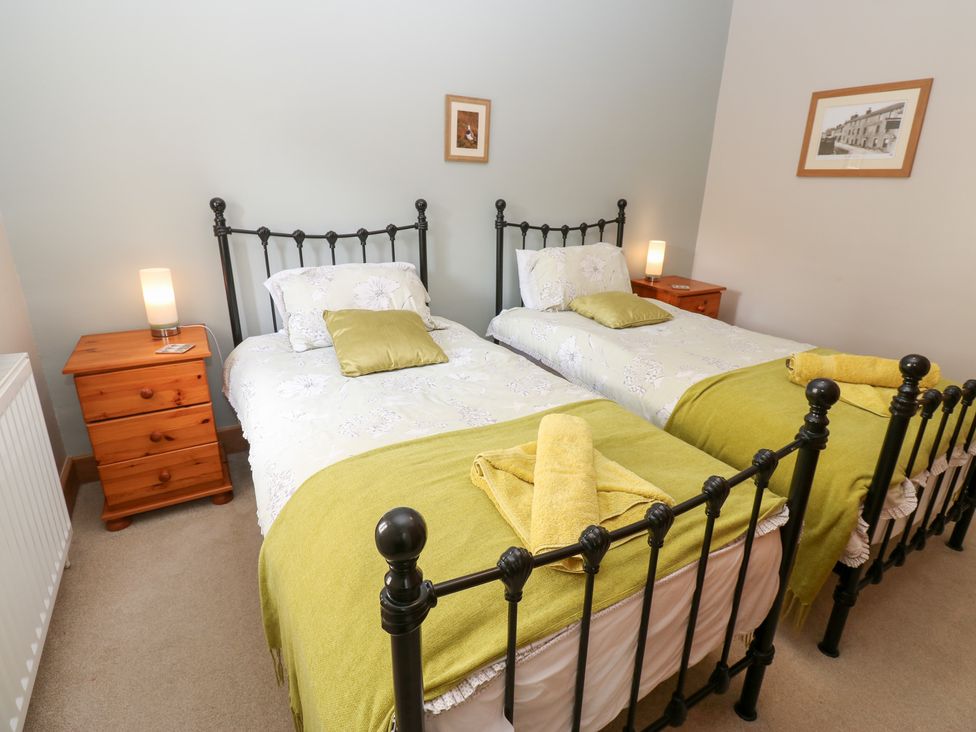 A bedroom with two beds and wooden furniture at Bridge House