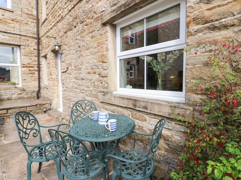 A table with chairs and cups outside next to a stone wall at Bridge House