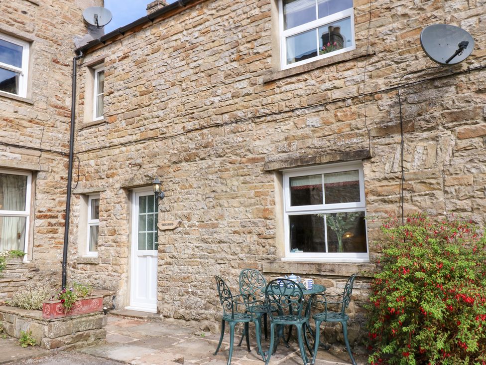 An outdoor setting with a table and chairs near a stone building at Bridge House