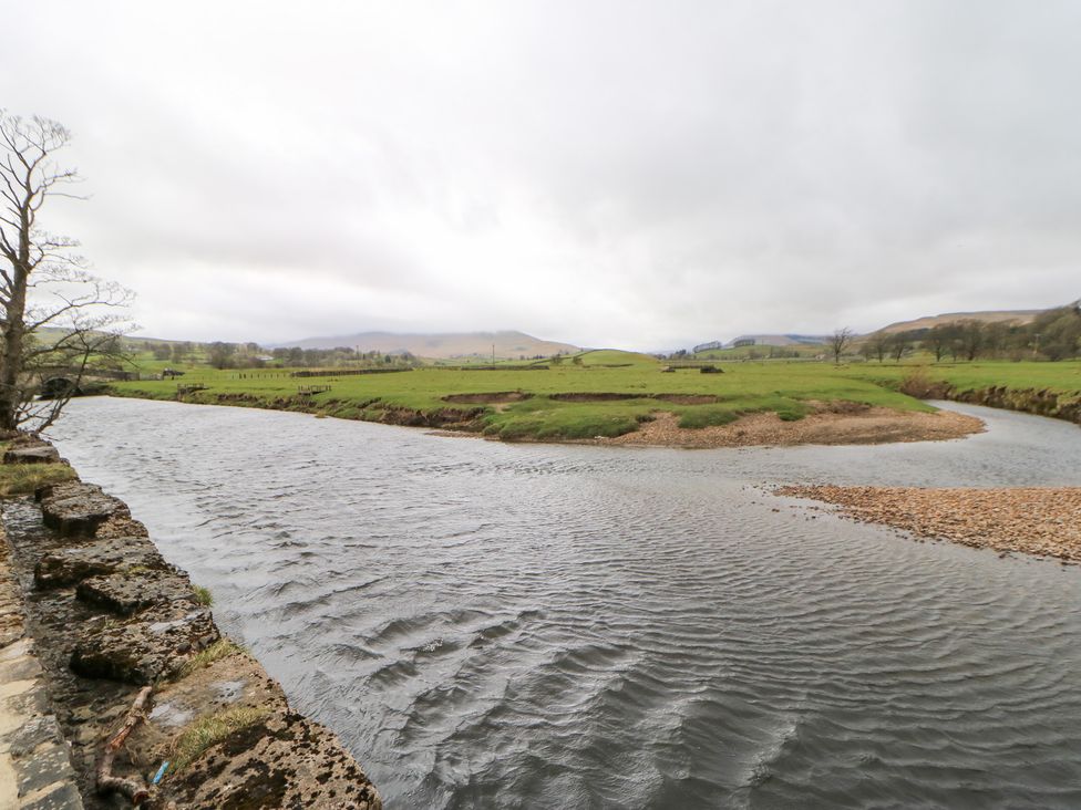 A river flowing through green fields and trees at Bridge House