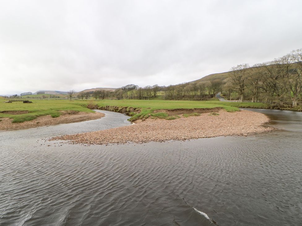 A river with gravel bank and grass with hills in the background at Bridge House