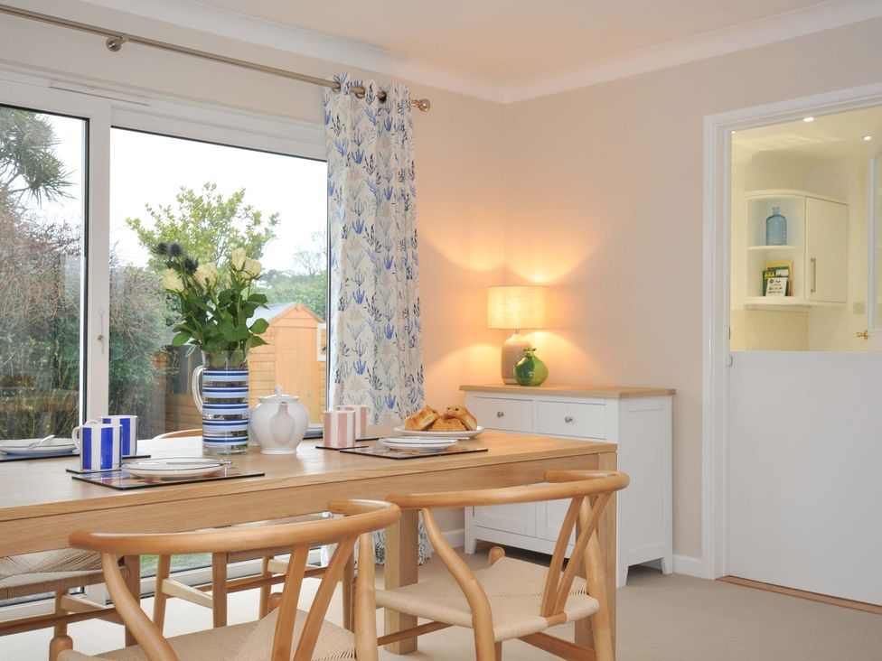 A dining room with a table and flowers at 42 Little Trelyn Rock