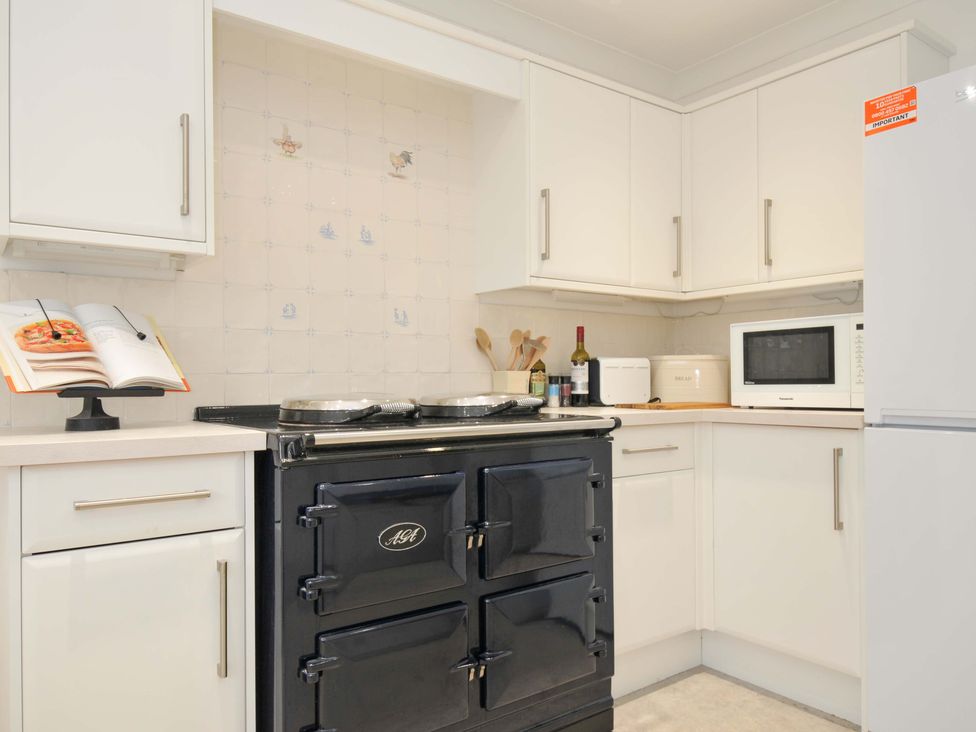 A kitchen with a black stove and microwave at 42 Little Trelyn in Rock