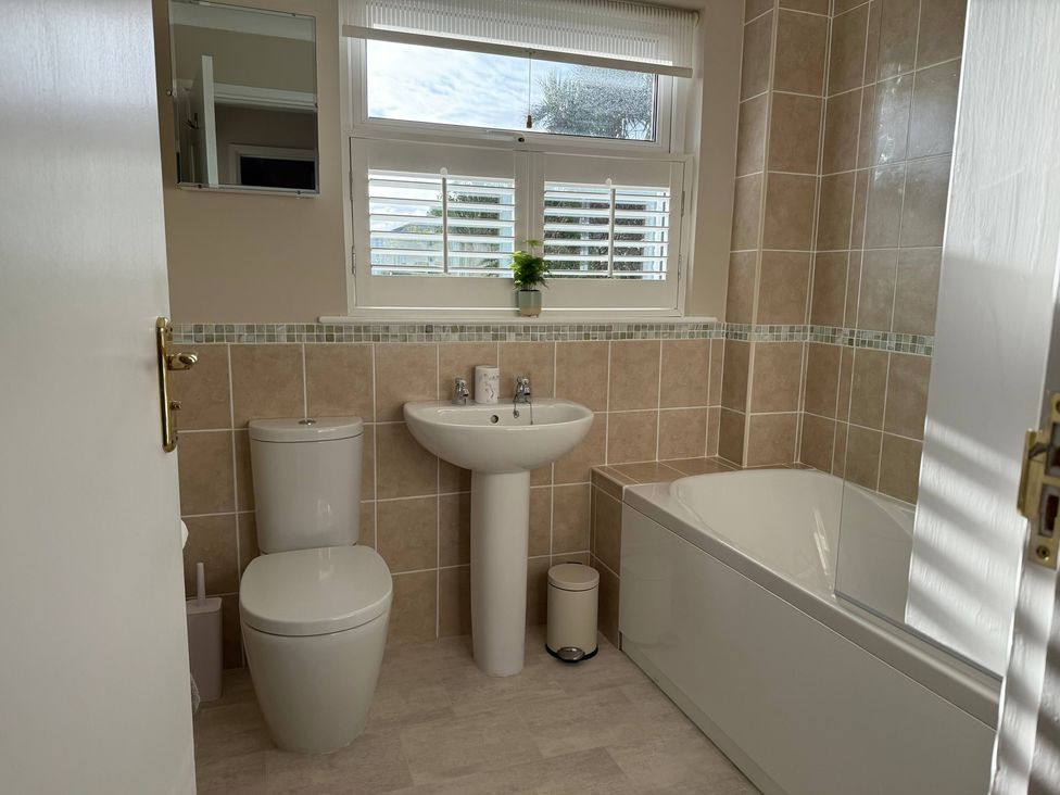 A bathroom with a sink, toilet, bathtub, and mirror at 42 Little Trelyn in Rock