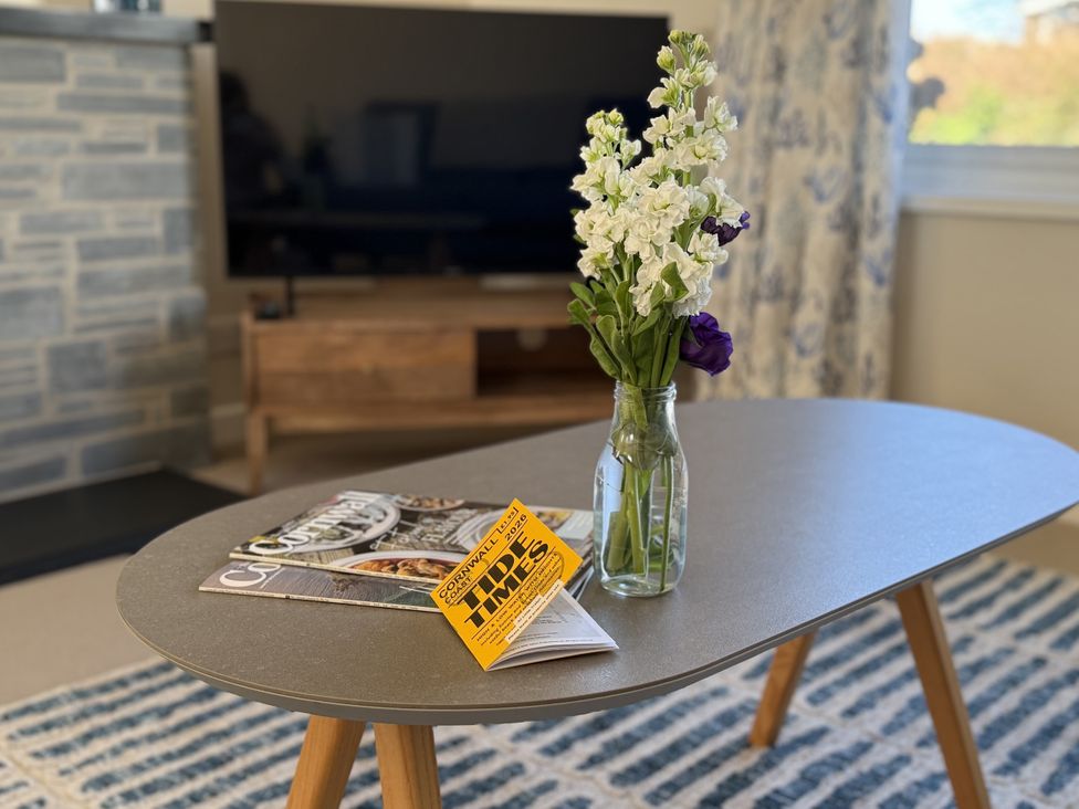 A living room with a coffee table, vase with flowers, and television at 42 Little Trelyn Rock