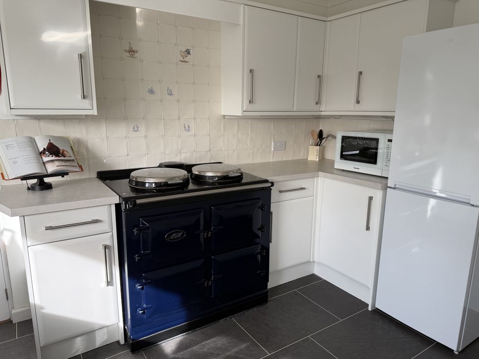 A kitchen with a blue cooker and microwave at 42 Little Trelyn Rock