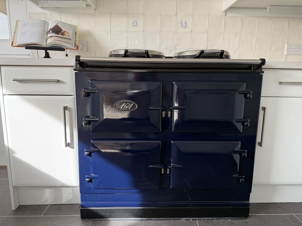 A blue oven with a recipe book in a kitchen at 42 Little Trelyn in Rock