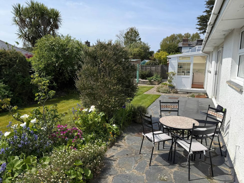 A garden with a table and chairs surrounded by flowers at 42 Little Trelyn, Rock