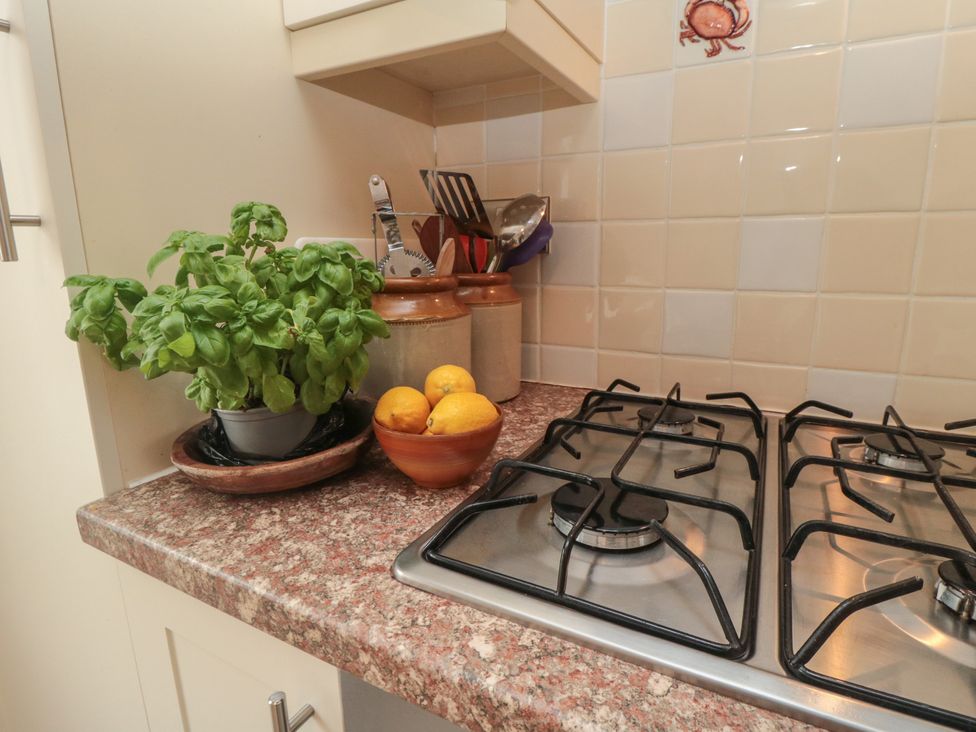 A kitchen countertop with a basil plant and a bowl of lemons at Iveridge Sandsend