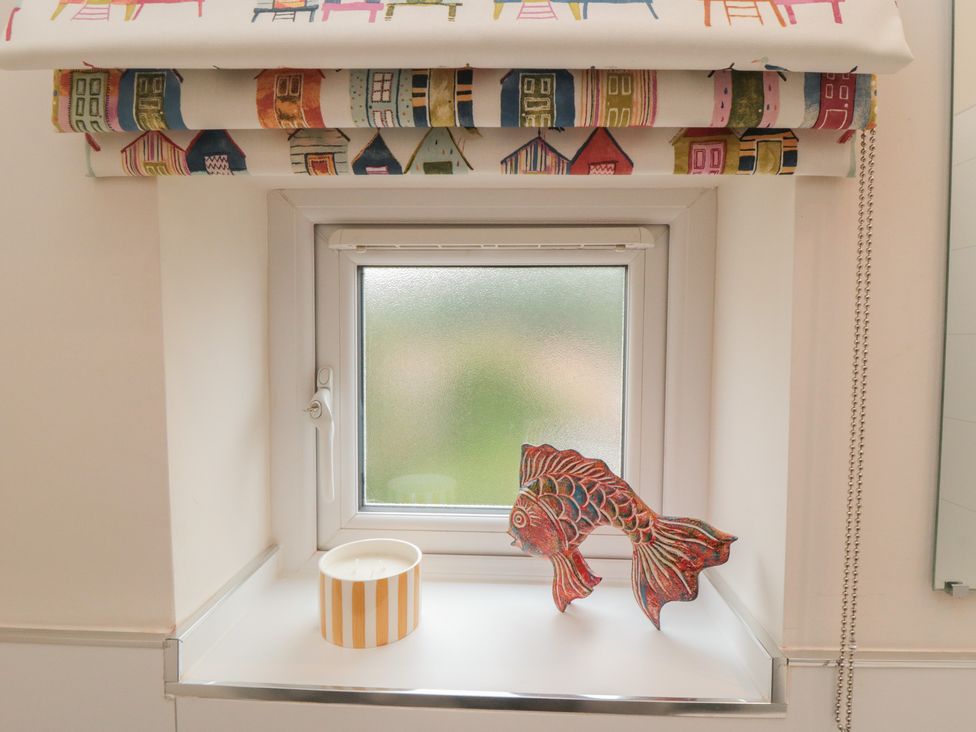 A bathroom window with a decorative fish and a candle at Iveridge in Sandsend