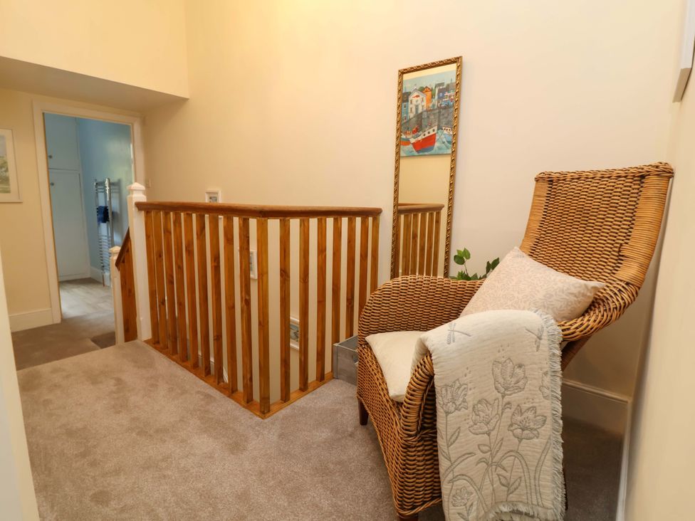 A hallway with a chair and mirror at Zide the Zea in Hele Bay, Ilfracombe