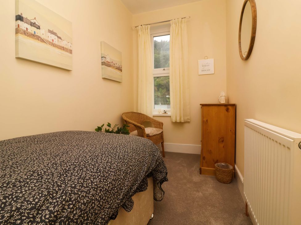 A bedroom with a bed, chair, and window at Zide the Zea in Hele Bay, Ilfracombe