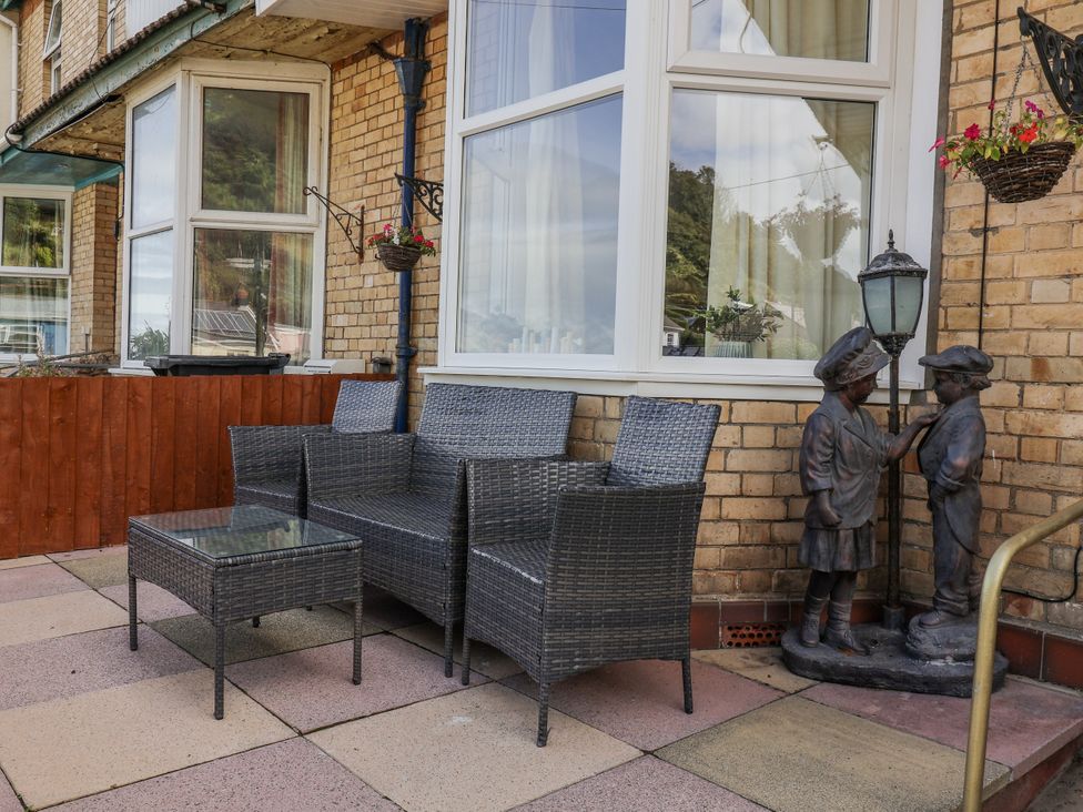 An outdoor seating area with a sofa set and statues at Zide the Zea in Hele Bay, Ilfracombe