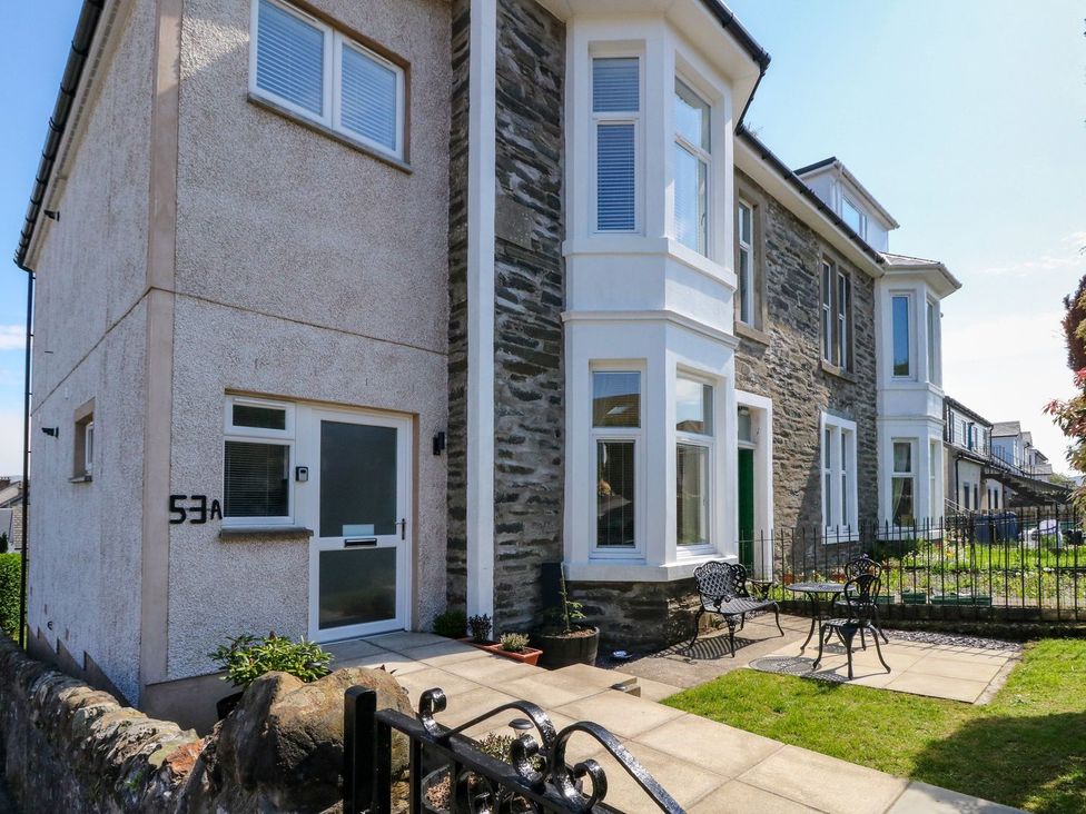 Front exterior of a stone and stucco house with a small garden area and metal outdoor furniture at Lenas Corner in Dunoon