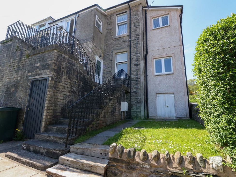 Outside view of a multi-story house with stone and brick walls stairs leading to a door and a small front lawn at Lena's Corner in Dunoon