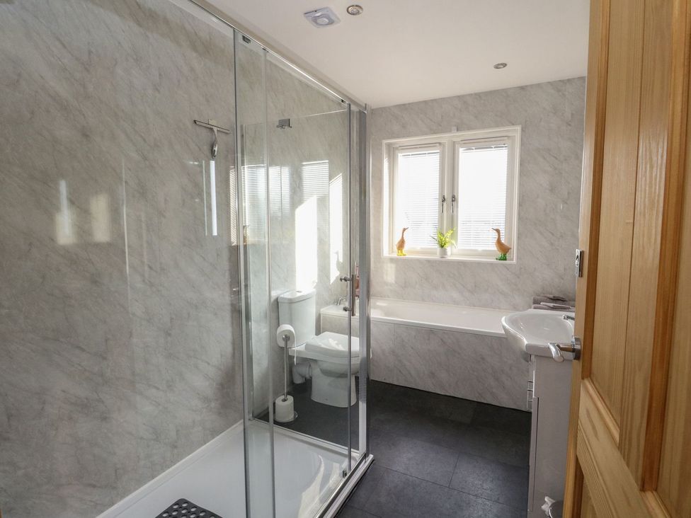 A bathroom with a shower enclosure a toilet a bathtub a sink and a window with blinds at Lenas Corner in Dunoon