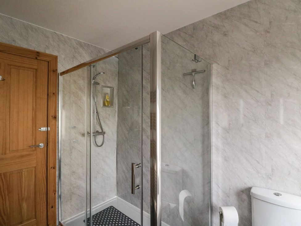 A bathroom with a glass shower enclosure a wooden door and a toilet at Lenas Corner in Dunoon