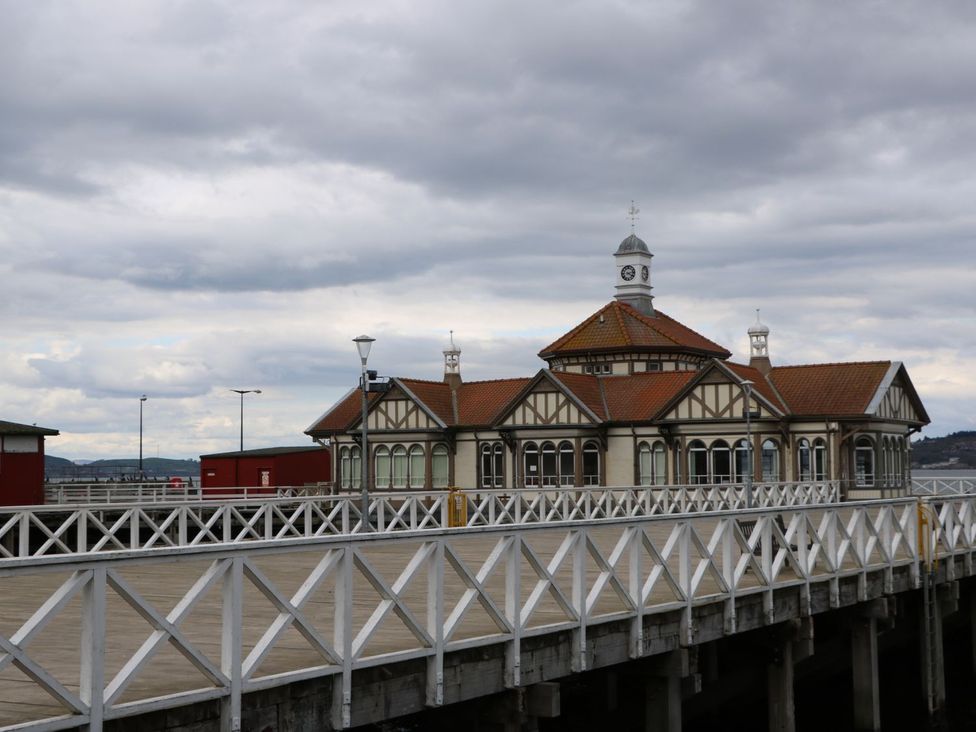 A pier with a building featuring a clock tower and cross-braced railings at Lena's Corner in Dunoon