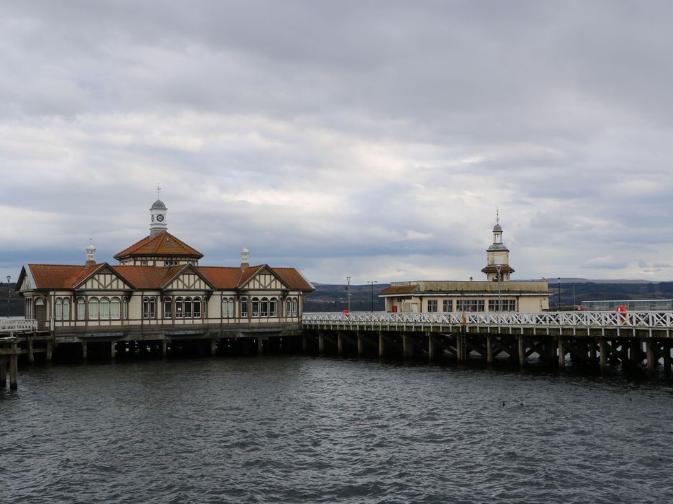 A pier with two buildings extending over the water with a cloudy sky