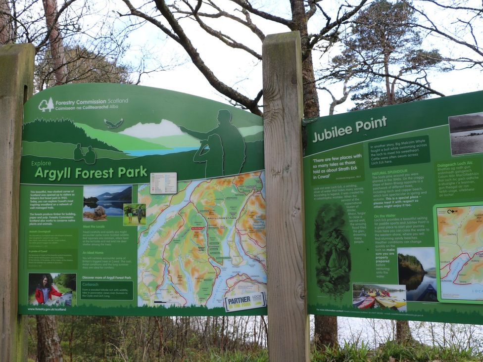 An information board with detailed maps and text about Argyll Forest Park and Jubilee Point in a forest setting at Lenas Corner in Dunoon