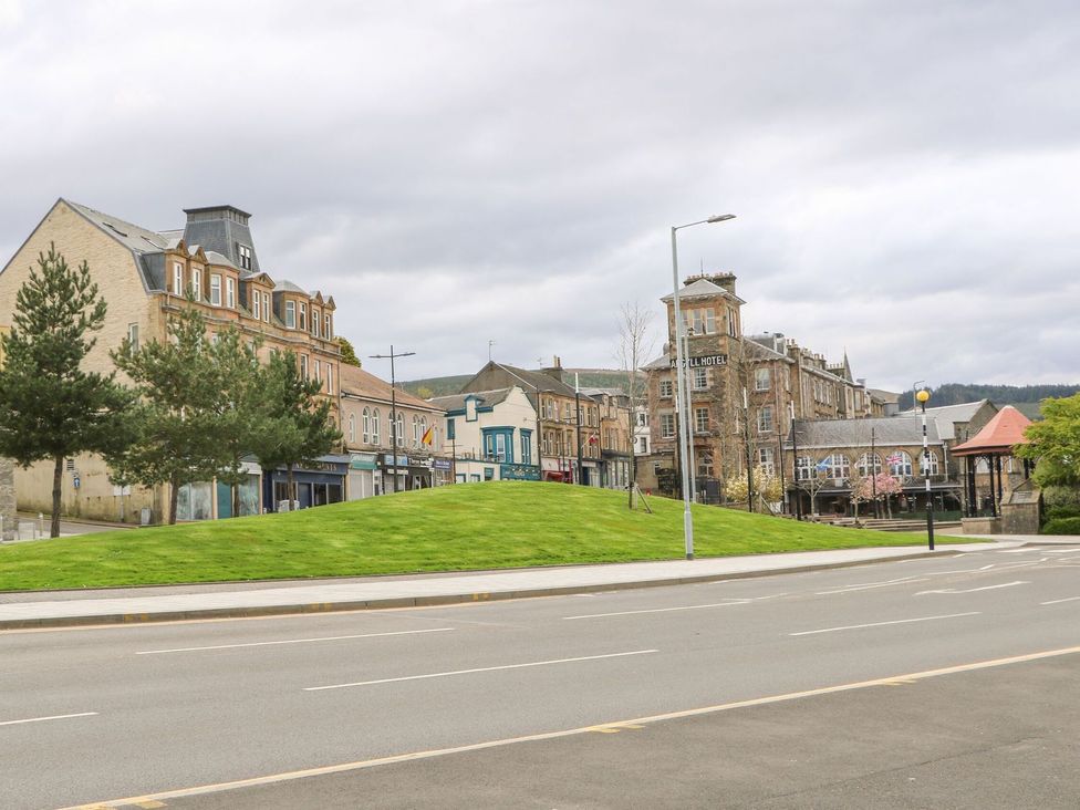A street with a grassy hill a row of buildings trees and a hotel at Lena's Corner in Dunoon