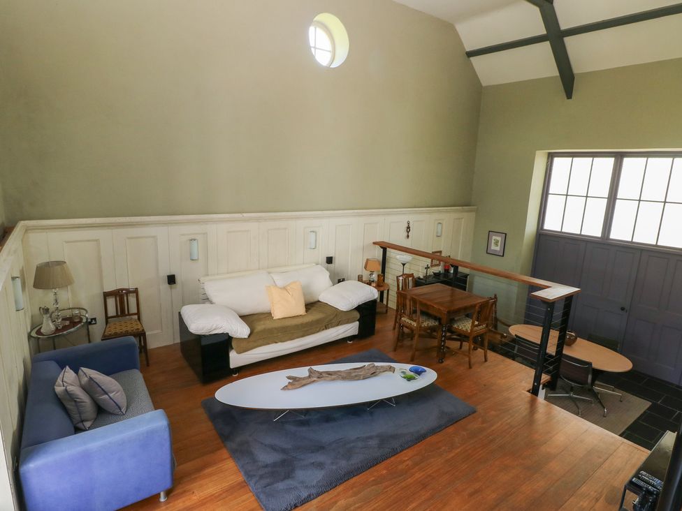 A two-level room with couches a coffee table a dining table and chairs a lamp and large windows at Zoar Chapel in Carew