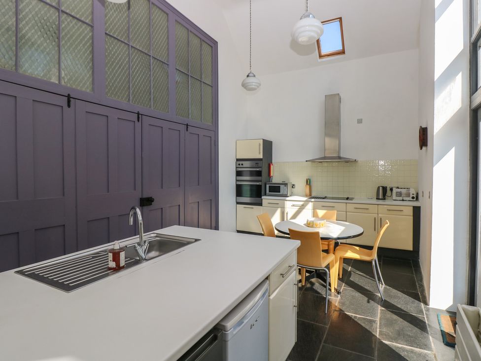 A kitchen with a sink island and a round dining table with four chairs at Zoar Chapel in Carew