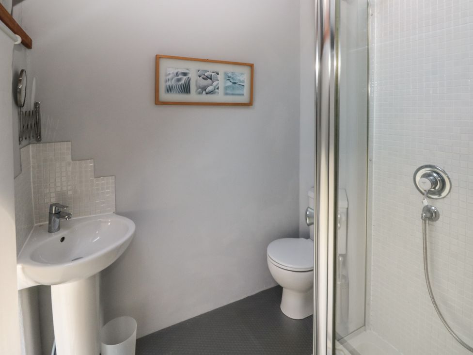 A bathroom with a pedestal sink a toilet a framed picture on the wall and a shower with glass door at Zoar Chapel in Carew