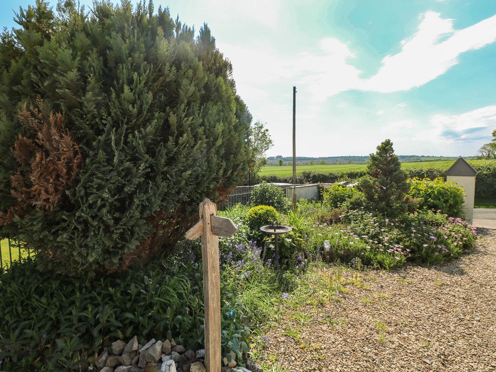 A garden with bushes flowers a bird bath and a wooden directional signpost at Zoar Chapel in Carew