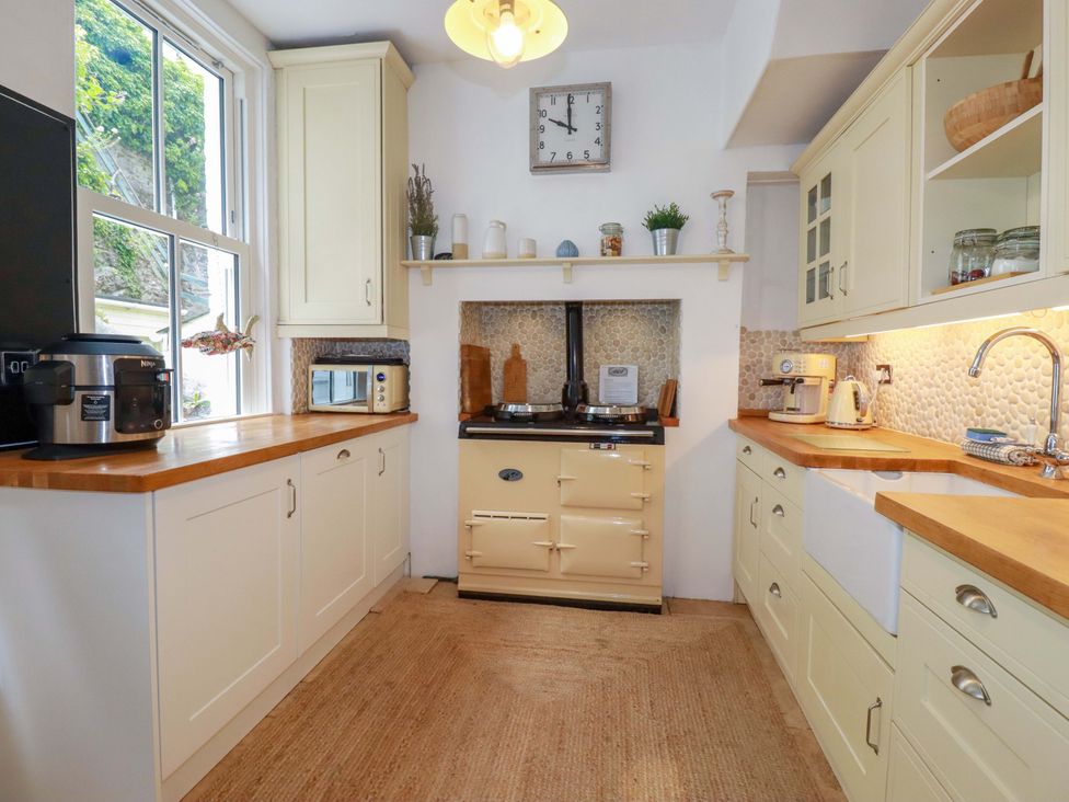 A kitchen with cabinets and appliances at Harbour House in Looe