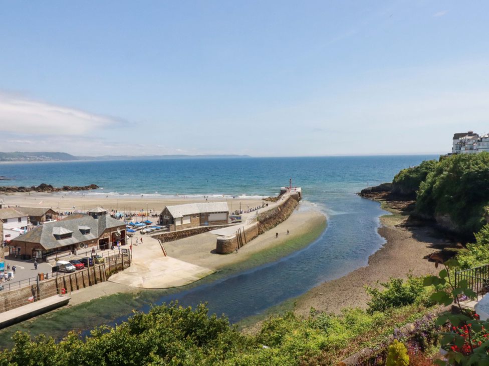A beach with a pier and buildings at Harbour House in Looe