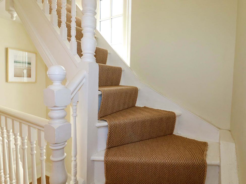 A staircase with carpet runner and handrail at Harbour House in Looe