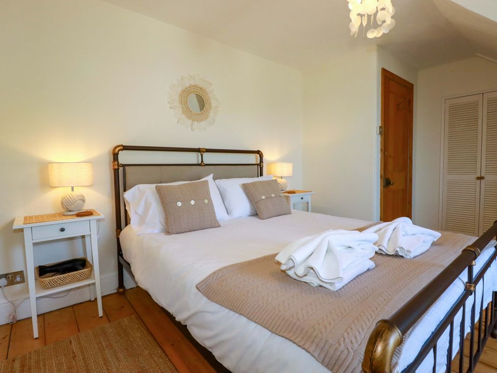 A bedroom with a bed and side table at Harbour House in Looe