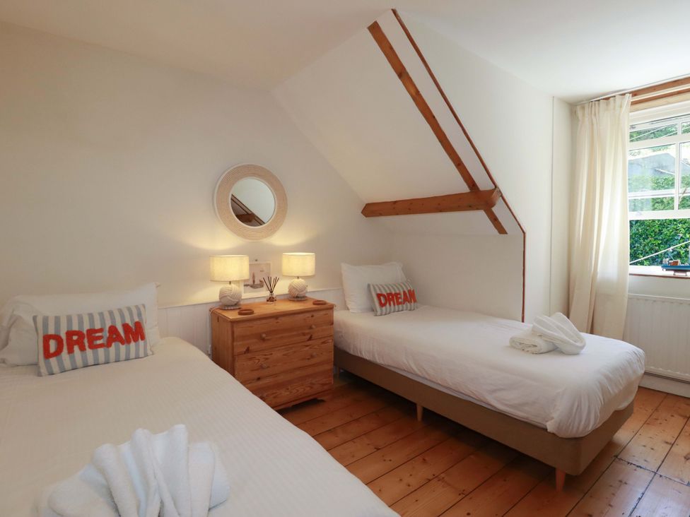 A bedroom with two beds and a nightstand at Harbour House in Looe