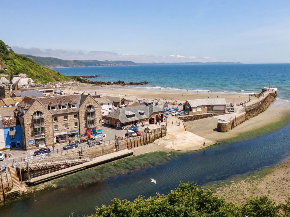 A beach with buildings and a pier at Harbour House in Looe