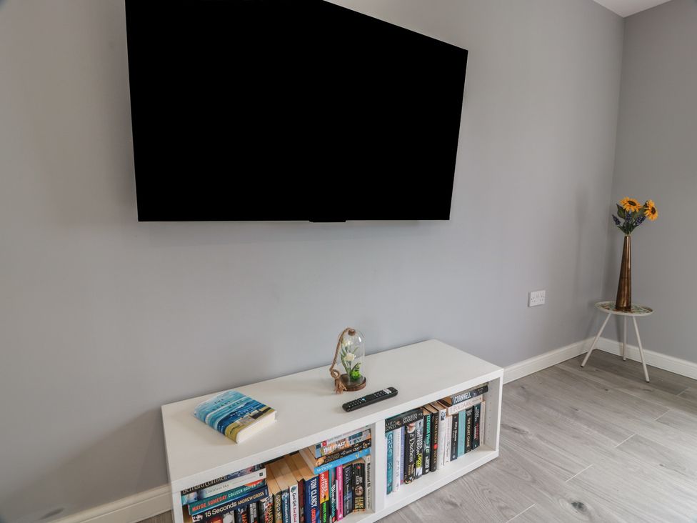 A living room with a TV and bookshelf at The Dairy in Airdrie