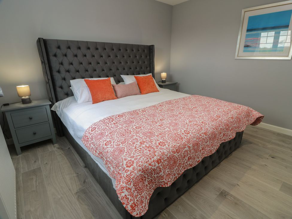 A bedroom with a large bed and nightstands at The Dairy Airdrie