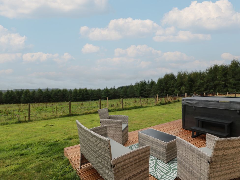A garden with chairs, a table and a hot tub at The Dairy in Airdrie