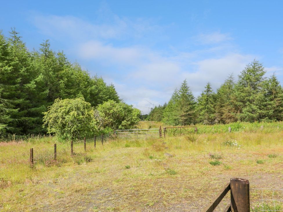 A path leading through grass and trees with a gate at The Dairy in Airdrie