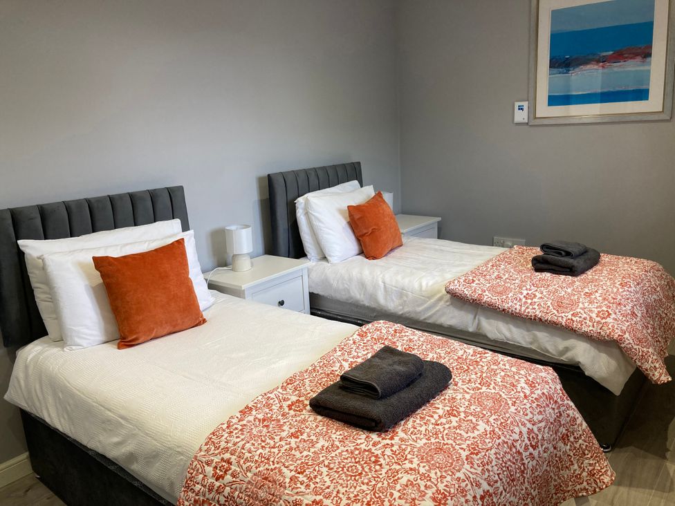 A bedroom with two beds and a bedside table at The Dairy in Caldercruix