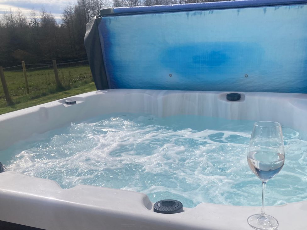 A hot tub with water and a glass at The Dairy in Caldercruix