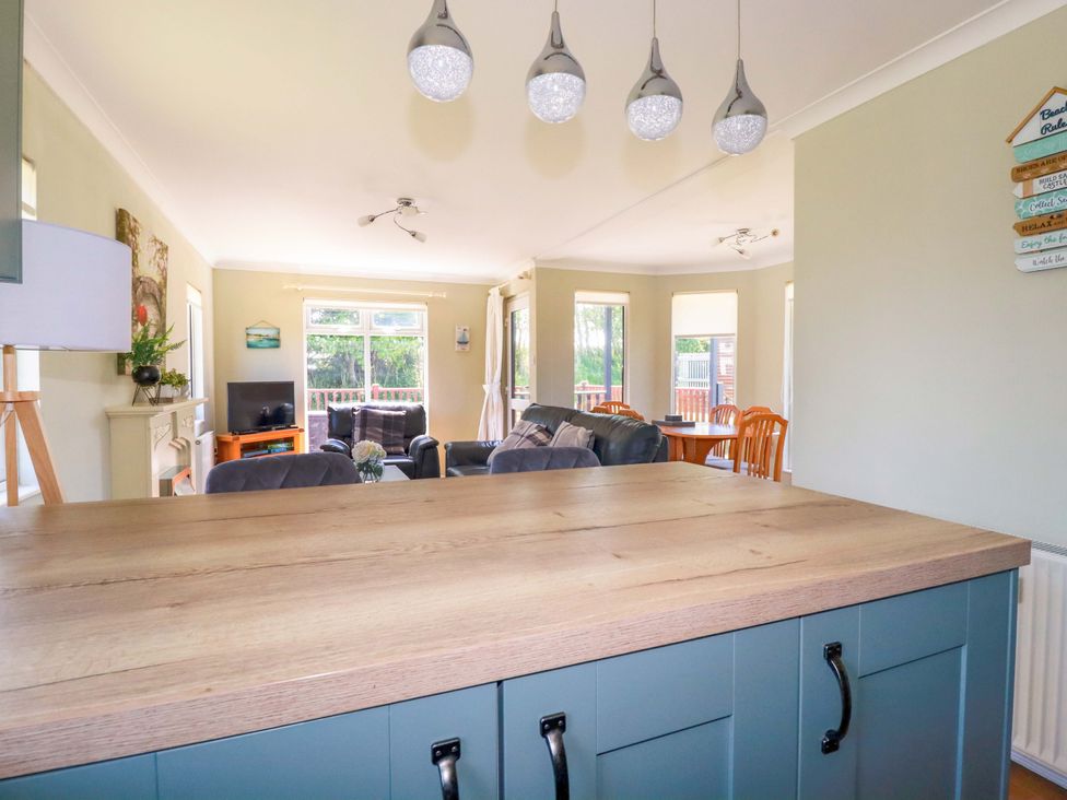 An open-plan living room and dining area with a wooden countertop and blue cabinets at Lodge 9- Lamorna in Tregolds near St Merryn