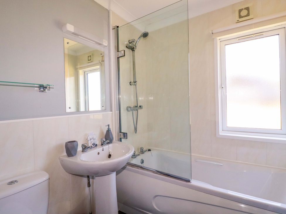 A bathroom with a bathtub and shower next to a sink and toilet at Lodge 9- Lamorna in Tregolds near St Merryn