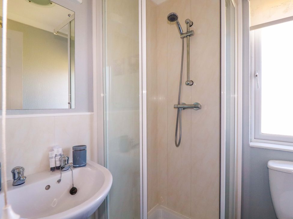A bathroom with a shower enclosure a sink with taps and a mirror above the sink at Lodge 9- Lamorna Tregolds near St Merryn