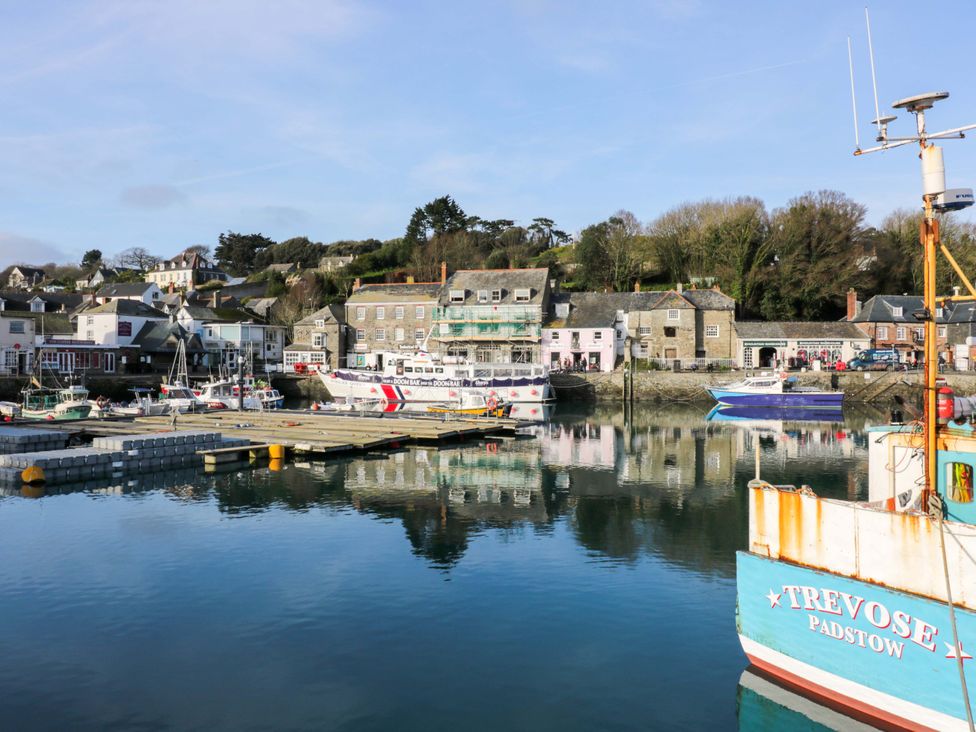 A harbor with boats docked near stone buildings and trees in the background at Lodge 9- Lamorna in Tregolds near St Merryn